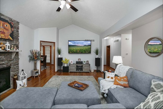 living room featuring lofted ceiling, a fireplace, dark wood-type flooring, and ceiling fan