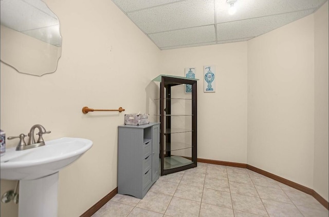 bathroom with a paneled ceiling, sink, and tile patterned floors