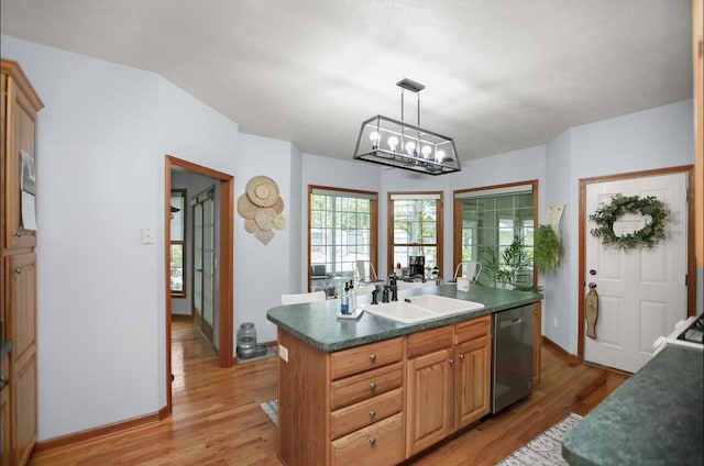 kitchen with light wood-type flooring, hanging light fixtures, a kitchen island with sink, and dishwasher