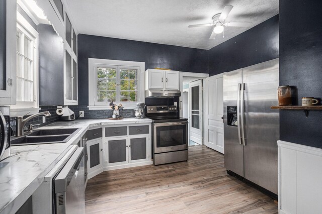 kitchen with white cabinets, backsplash, stainless steel appliances, hardwood / wood-style floors, and sink