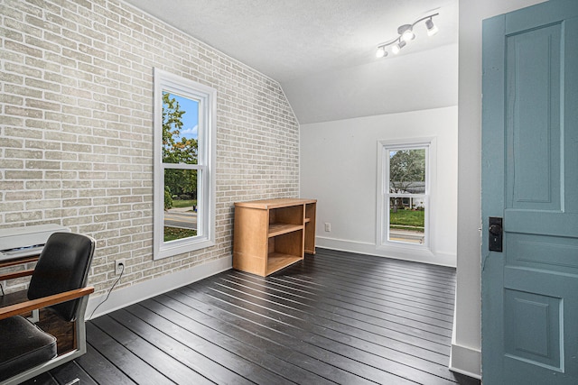 office area featuring brick wall, a textured ceiling, lofted ceiling, and dark hardwood / wood-style floors