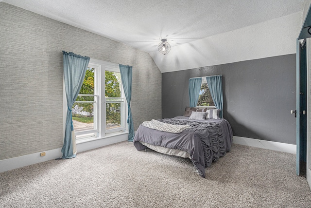 bedroom with carpet flooring, a textured ceiling, and vaulted ceiling