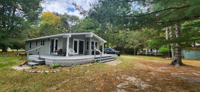 rear view of property with a storage shed, a yard, and a wooden deck