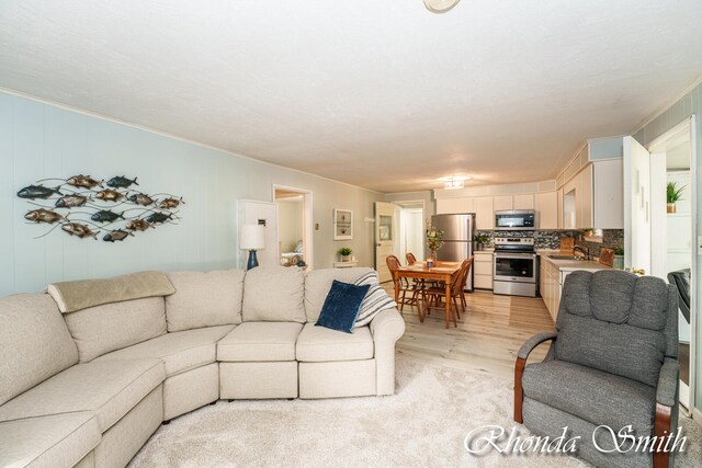 living room featuring ornamental molding, sink, and light hardwood / wood-style floors