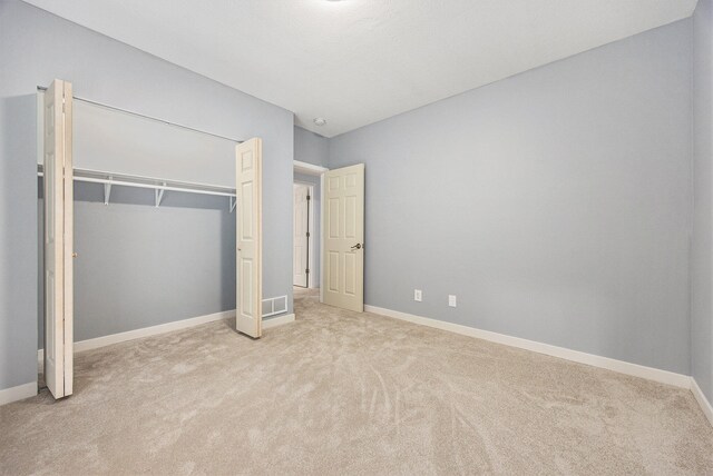 unfurnished bedroom featuring light carpet and a closet