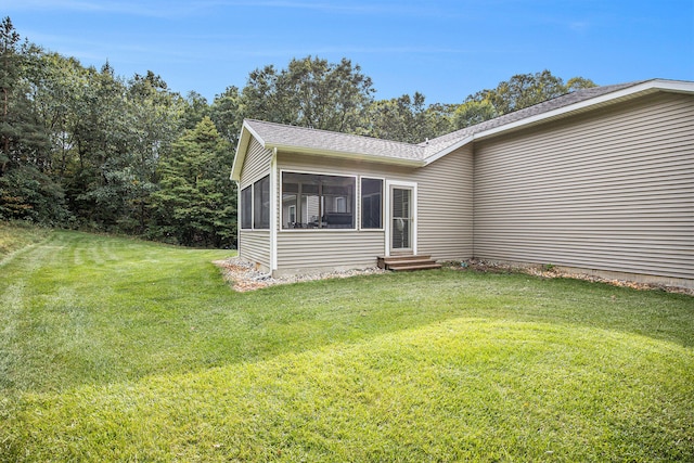 view of home's exterior with a sunroom and a lawn