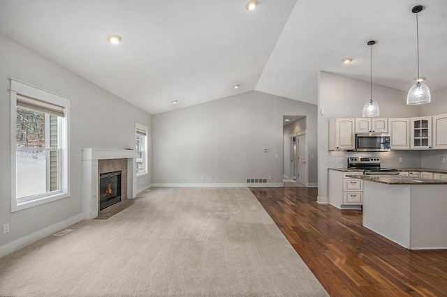 kitchen featuring dark wood-type flooring, white cabinetry, dark stone countertops, appliances with stainless steel finishes, and a tile fireplace