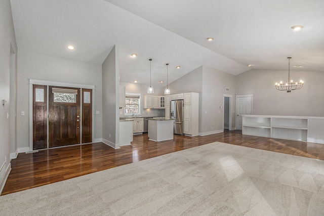 carpeted foyer featuring high vaulted ceiling and a notable chandelier