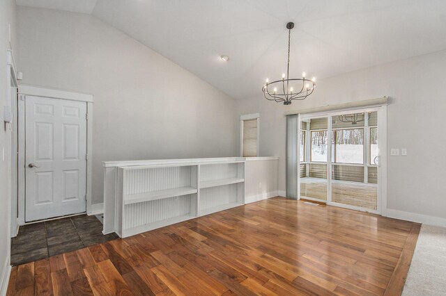 empty room with vaulted ceiling, a notable chandelier, and dark hardwood / wood-style flooring