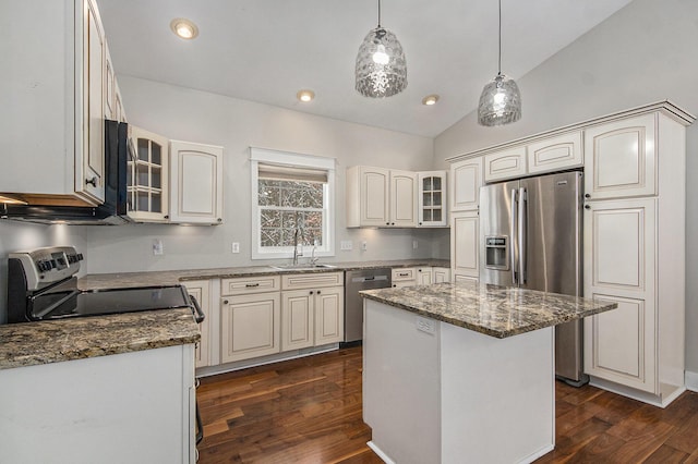 kitchen with appliances with stainless steel finishes, a center island, sink, and dark stone counters