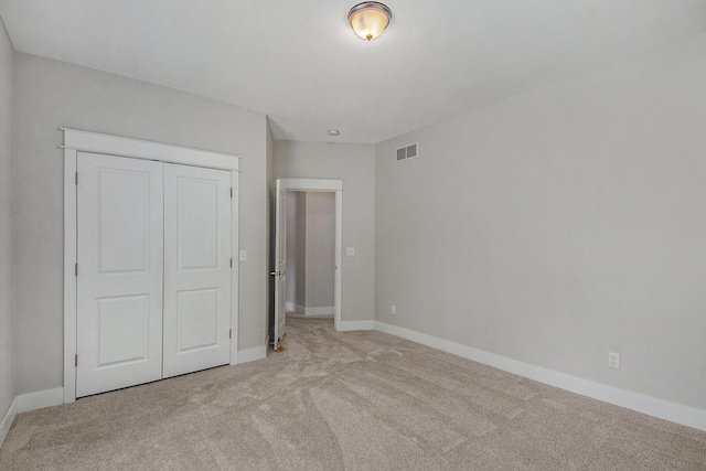 unfurnished bedroom featuring light colored carpet and a closet