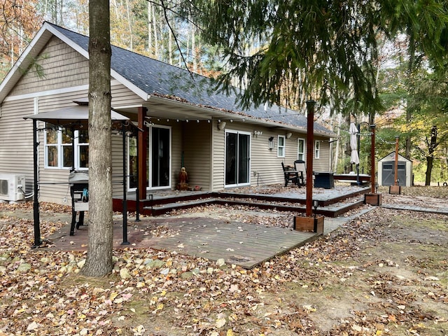 rear view of house with ac unit, a storage unit, and a wooden deck