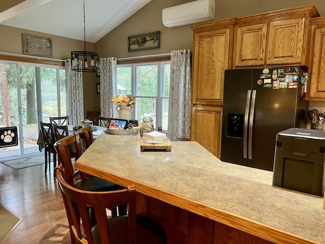 interior space with decorative light fixtures, a healthy amount of sunlight, stainless steel fridge with ice dispenser, and an AC wall unit