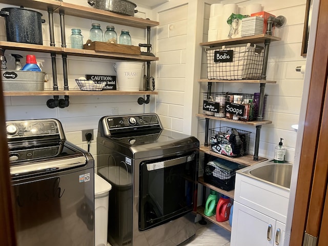 clothes washing area with cabinets, sink, and washer and dryer