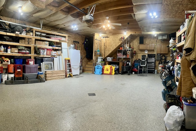 garage with white refrigerator, a garage door opener, and a workshop area