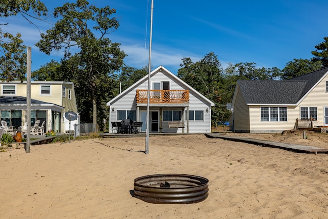 back of property featuring a balcony and an outdoor fire pit