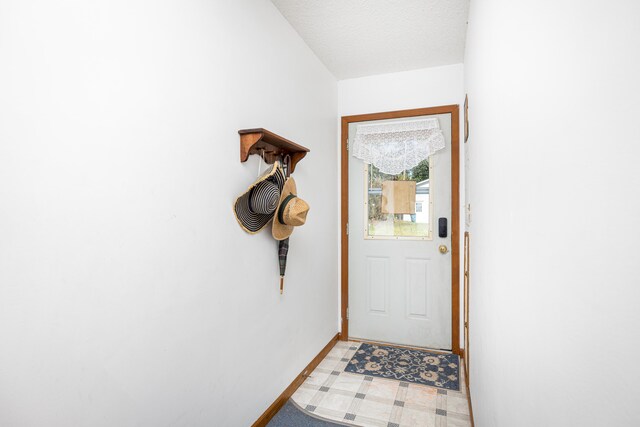 doorway to outside with a textured ceiling