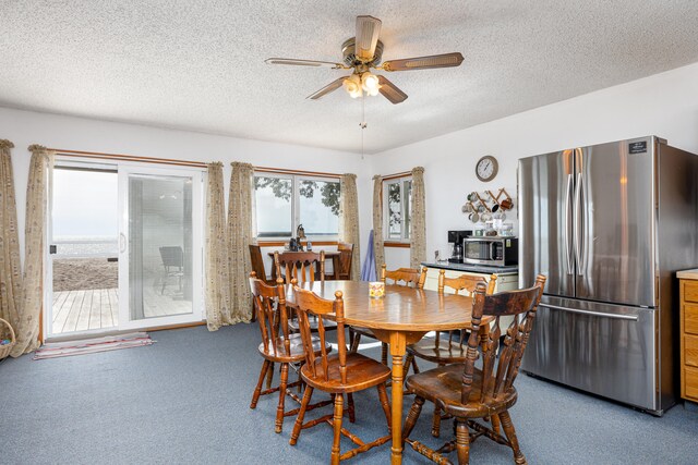 carpeted dining area with ceiling fan and a textured ceiling