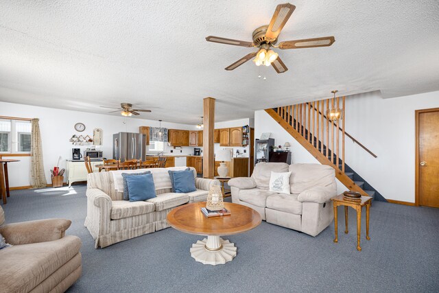 carpeted living room featuring a textured ceiling and ceiling fan with notable chandelier