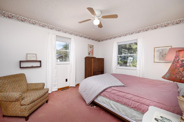 carpeted bedroom featuring multiple windows, a textured ceiling, and ceiling fan