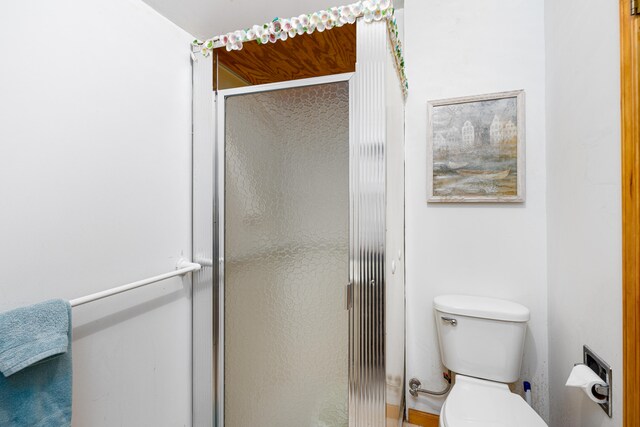 bathroom with a shower with door and toilet