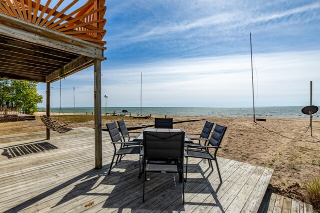 wooden terrace featuring a beach view and a water view