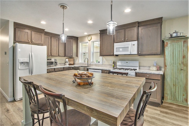 kitchen featuring sink, pendant lighting, light hardwood / wood-style flooring, and white appliances