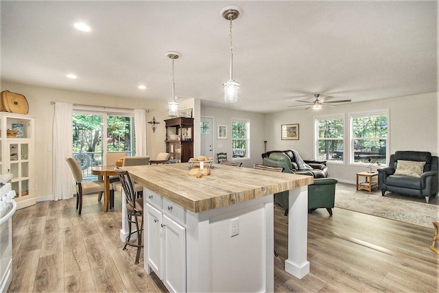 kitchen featuring pendant lighting, white cabinets, a center island, a kitchen breakfast bar, and ceiling fan