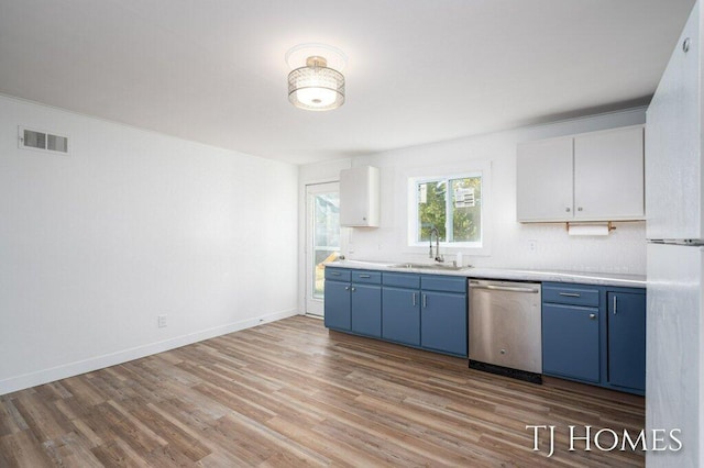 kitchen with light wood-type flooring, sink, white cabinets, blue cabinetry, and stainless steel dishwasher