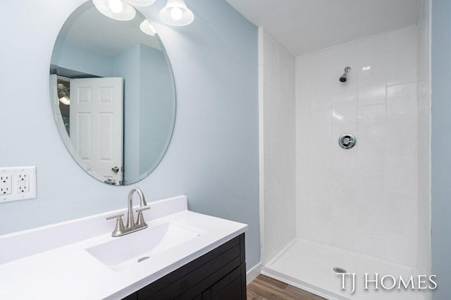 bathroom featuring vanity, hardwood / wood-style floors, and a tile shower