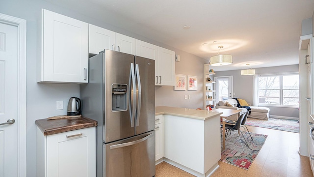 kitchen with white cabinets, stainless steel fridge, decorative light fixtures, and kitchen peninsula