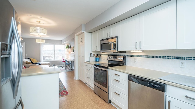 kitchen with pendant lighting, appliances with stainless steel finishes, white cabinets, and tasteful backsplash