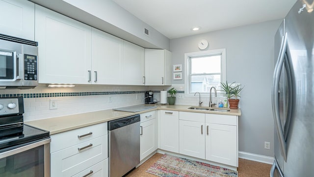 kitchen with stainless steel appliances, white cabinetry, sink, and tasteful backsplash