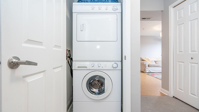 washroom featuring stacked washer / dryer and carpet