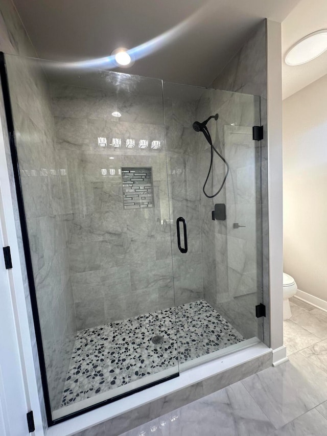 bathroom with a shower with shower door and toilet