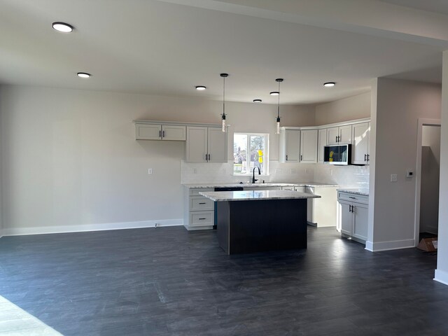 kitchen with light stone countertops, sink, white cabinets, a center island, and hanging light fixtures