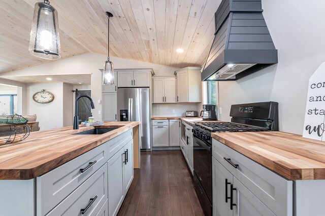 kitchen featuring premium range hood, black gas range oven, hanging light fixtures, and wooden counters