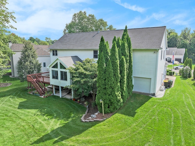 exterior space featuring a wooden deck, a garage, and a yard