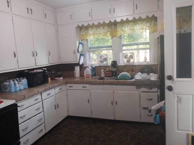 kitchen featuring black appliances, white cabinets, crown molding, and tile countertops