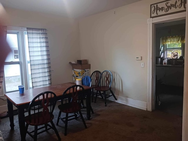 dining space featuring dark colored carpet and a healthy amount of sunlight