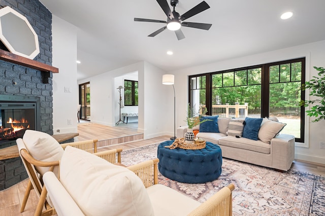 living room featuring ceiling fan, light hardwood / wood-style floors, and a fireplace