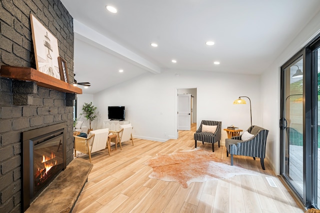 living area with vaulted ceiling with beams, light wood-type flooring, and a large fireplace