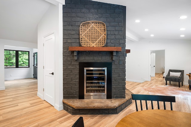 bar featuring light wood-type flooring, vaulted ceiling with beams, a fireplace, and wine cooler