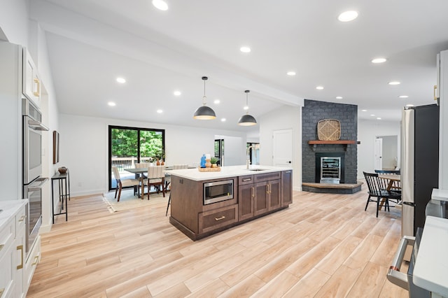 kitchen featuring appliances with stainless steel finishes, hanging light fixtures, and light wood-type flooring