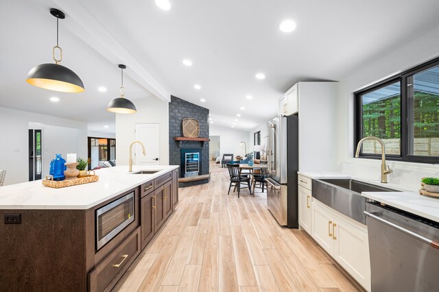 kitchen with sink, white cabinets, hanging light fixtures, vaulted ceiling with beams, and appliances with stainless steel finishes