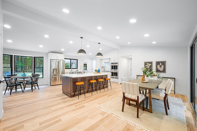 dining space featuring light hardwood / wood-style flooring, lofted ceiling with beams, and sink