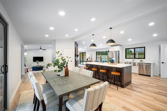 dining area featuring ceiling fan, sink, lofted ceiling, and light hardwood / wood-style floors