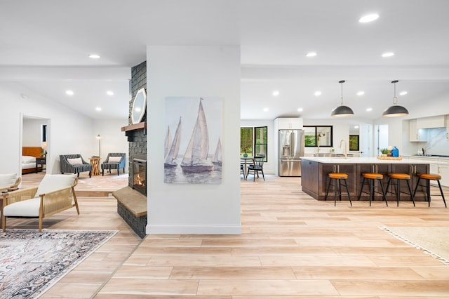 living room featuring a stone fireplace, sink, and light hardwood / wood-style floors