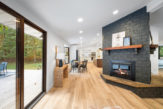 living room featuring a fireplace, vaulted ceiling, and light hardwood / wood-style flooring