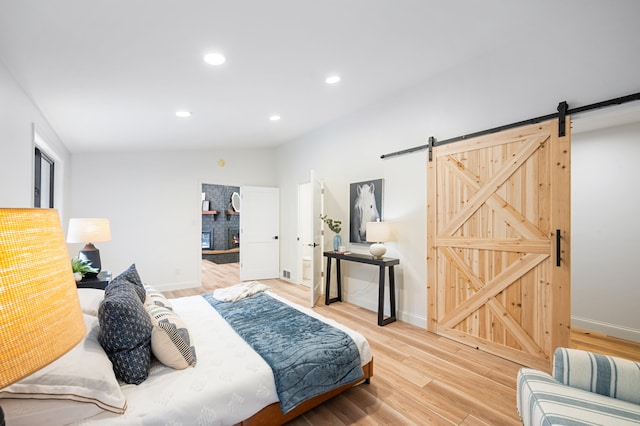 bedroom with a barn door, lofted ceiling, and hardwood / wood-style floors